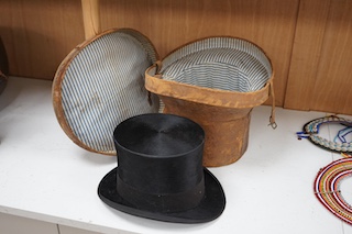 A gentleman’s black silk top hat with a black felt band and, cream silk lining, together with a brown leather case, hat height 17cm. Condition - silk brim worn in various places, leather case very poor